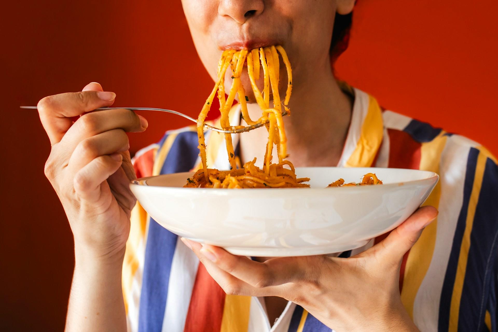 Le garçon mange un délicieux plat de pâtes.
