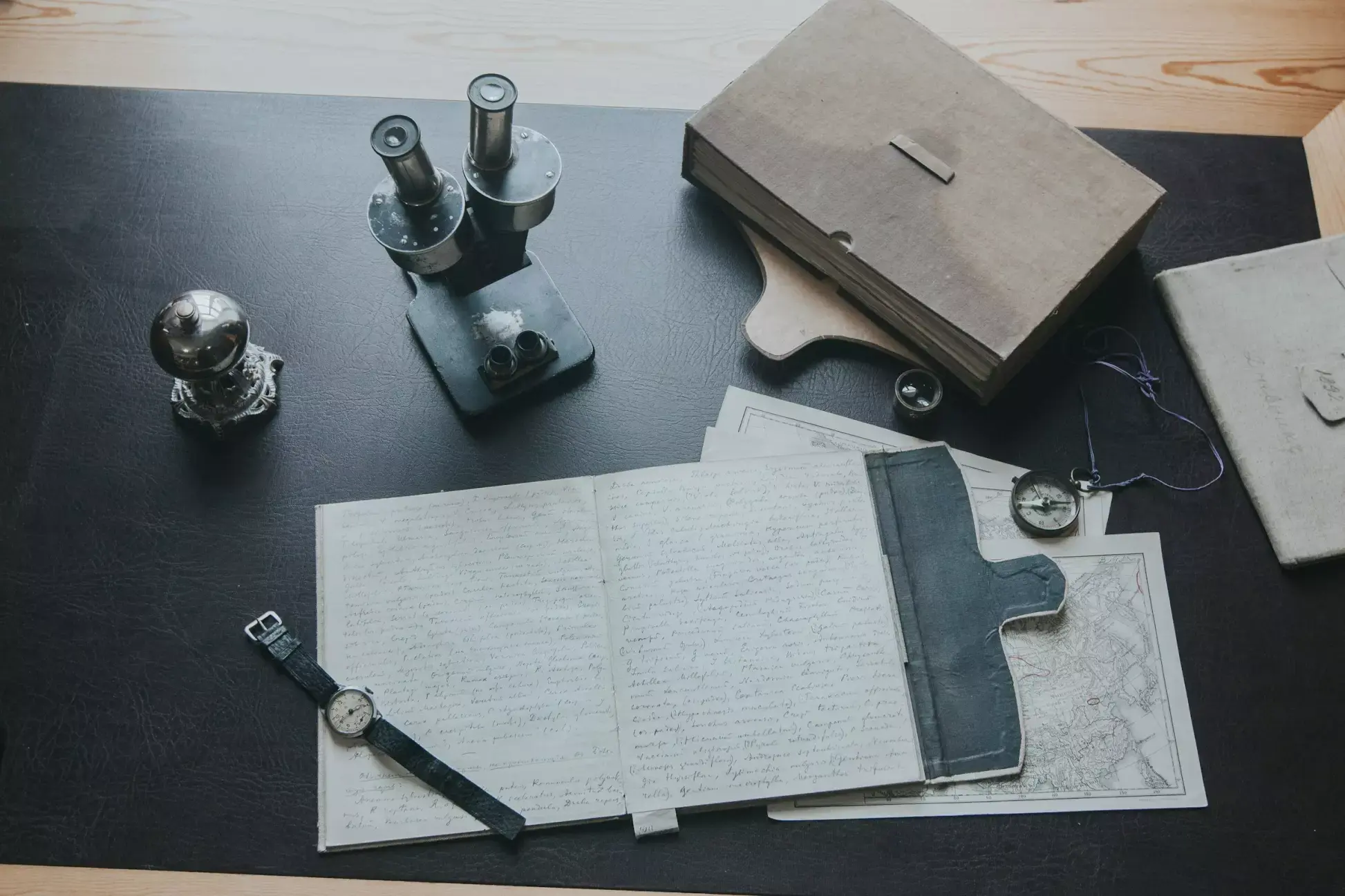 Bureau avec ordinateur portable, montres, livre et microscope.